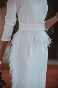 Vestido midi blanco con manga larga y pluma en cintura y falda