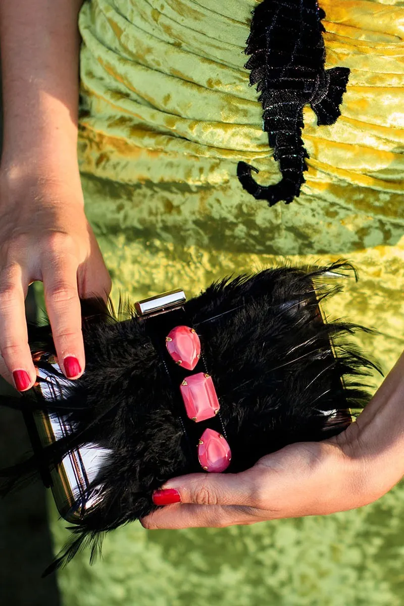 clutch de fiesta dorado con plumas negras y piedras frambuesa