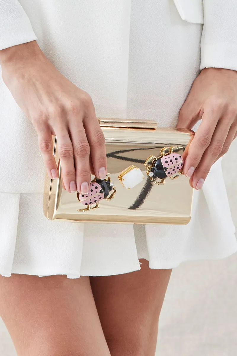 clutch de fiesta dorado con insecto joya rosa y negro y piedra