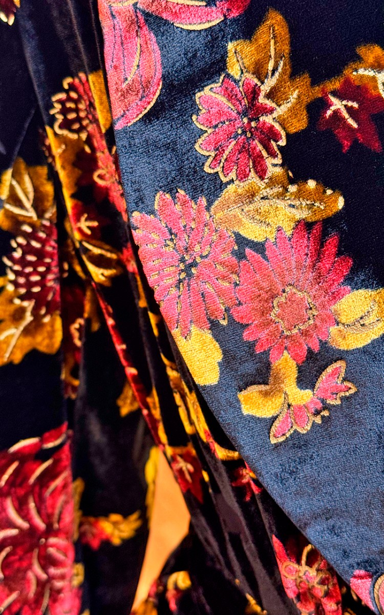 chaqueta confeccionada en terciopelo negro con un estampado de flores rojas y amarillas por todo el traje para eventos de invierno